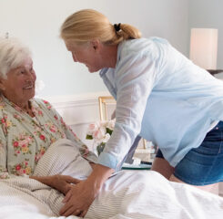 Woman talking with older adults woman in bed in hospice setting