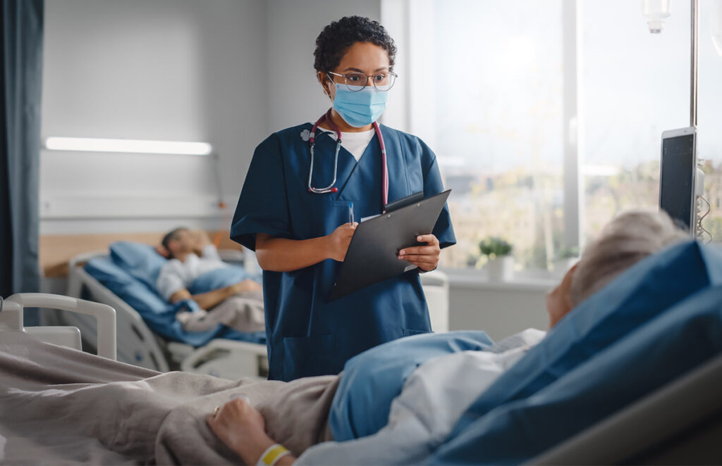 Medical professional talks with male patient in shared room