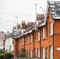 Row of brick townhomes with dusting of snow on rooves.