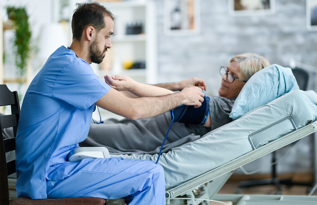 caregiver treating senior woman evaluating blood pressure 1200 776