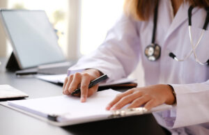 doctor reviewing paperwork at desk 1200 776