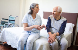 elderly man speaking with caretaker wheelchair in background 1207052059 1200 776