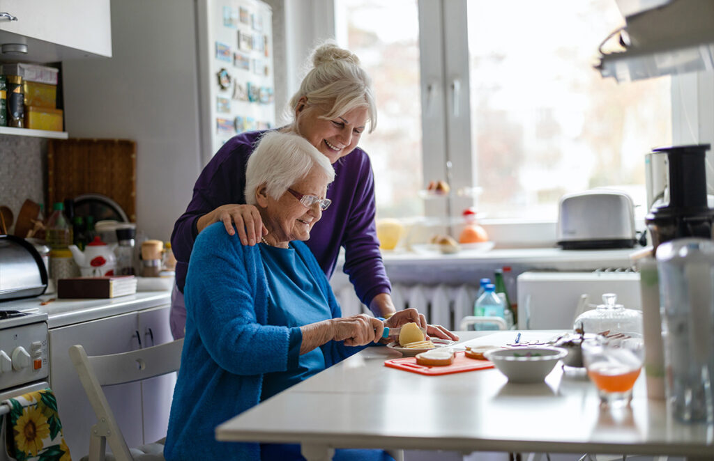 elderly woman cutting food in kitchen with daughter 1446888331 1200 776