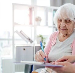 nursing home worker assisting senior resident with paperwork 1200 776
