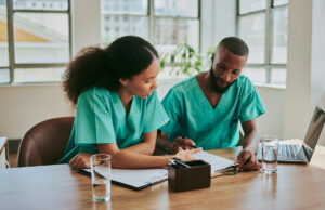 two medical workers reading files discussing 1500306553 1200 776