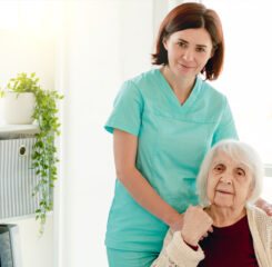 caregiver standing beside elderly woman on chair 1200 776