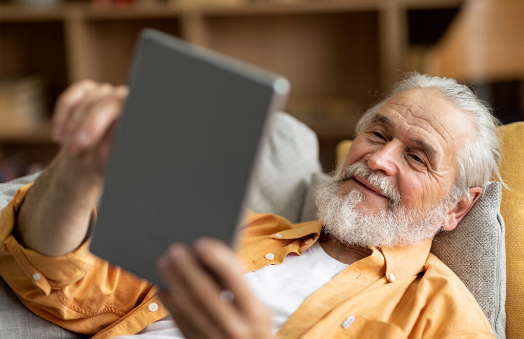cheerful senior man using digital tablet at home 1200 776