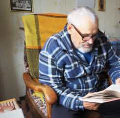 elderly man reads a book sitting in a comfortable chair 1200 776