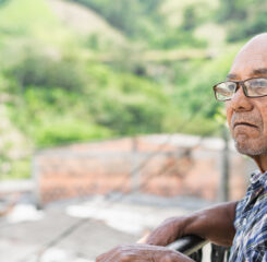 elderly man with brown skin and glasses standing outdoors 1200 776