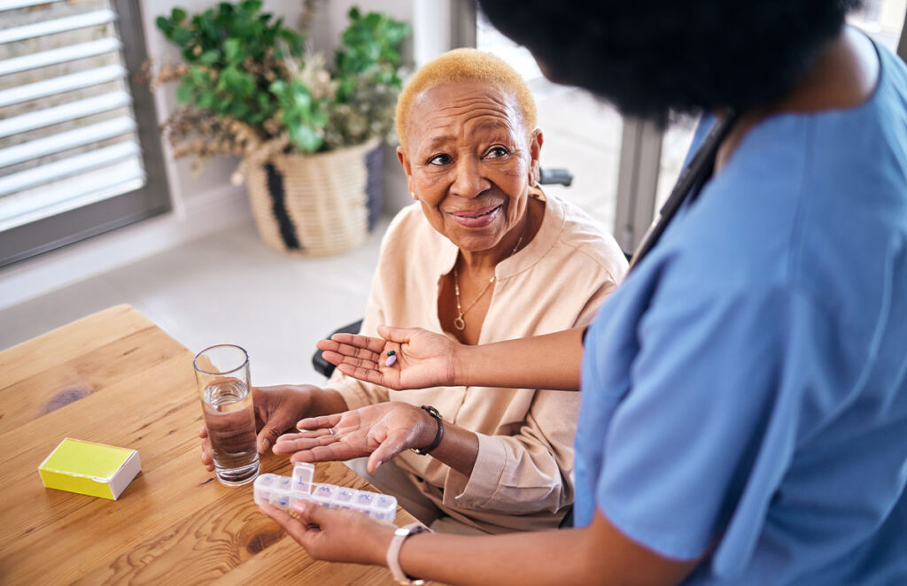 nurse smile and giving old woman pills in home 1200 776