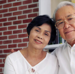 portrait of happy asian elderly couple sitting on couch 1200 776