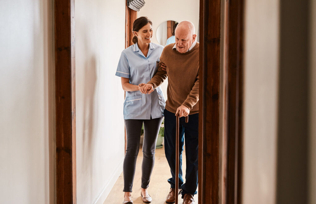 Caregiver helping resident walk 1184374883 1200 776